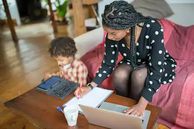 madre soltera trabajando en su computadora, con su hijo a lado.