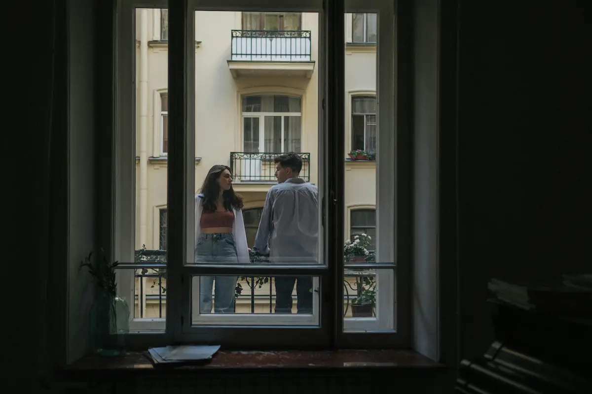 Pareja en un balcón hablando seriamente, simbolizando la comunicación y el espacio personal.